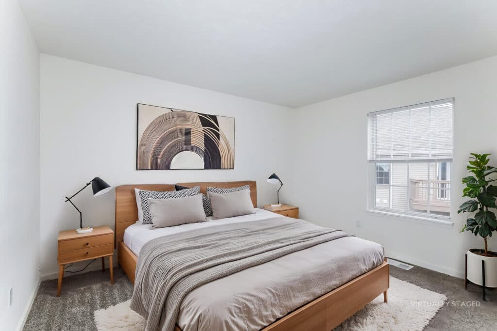 A modern bedroom with a wooden bed, neutral bedding, two nightstands with lamps, a large abstract artwork, a window, and a potted plant.